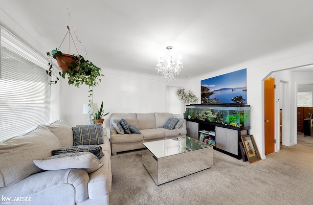 carpeted living room with a wealth of natural light and an inviting chandelier