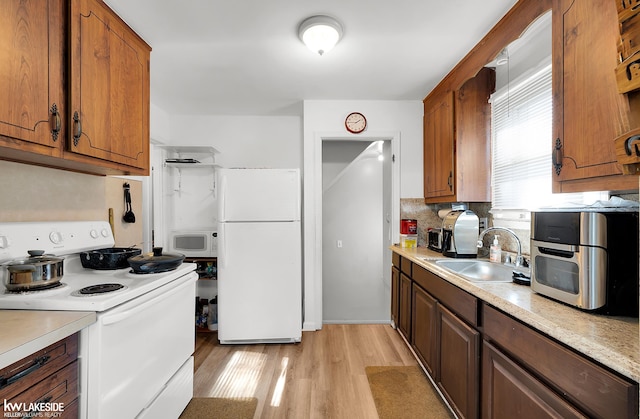 kitchen with light wood-type flooring, backsplash, sink, and white appliances