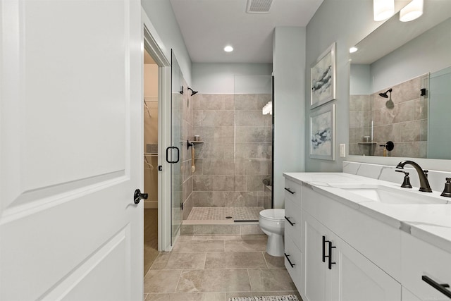 bathroom with tile patterned flooring, a shower with shower door, vanity, and toilet