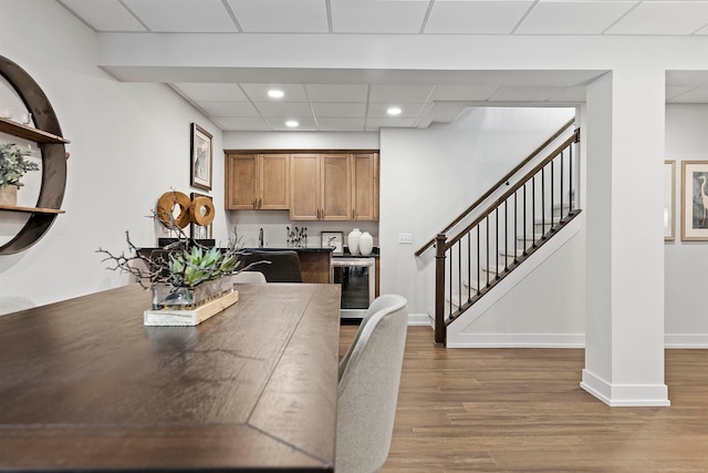 dining area featuring wine cooler, a drop ceiling, and hardwood / wood-style floors