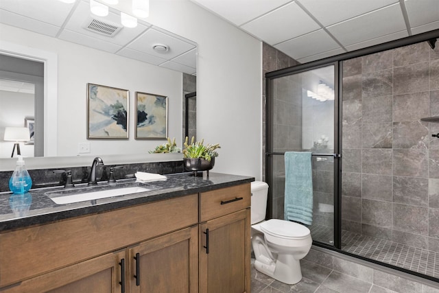 bathroom featuring vanity, walk in shower, a drop ceiling, tile patterned flooring, and toilet