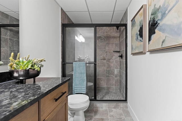 bathroom featuring vanity, an enclosed shower, a drop ceiling, tile patterned floors, and toilet