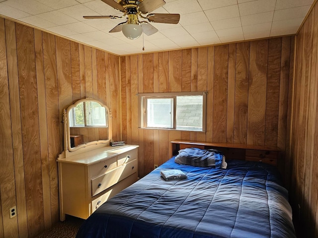 bedroom featuring ceiling fan and wood walls