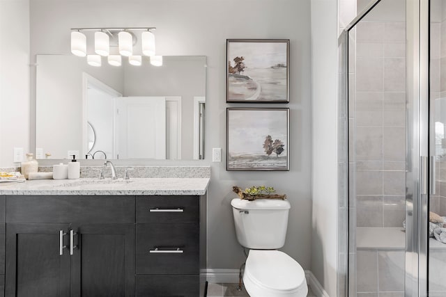 bathroom featuring a shower with shower door, vanity, and toilet