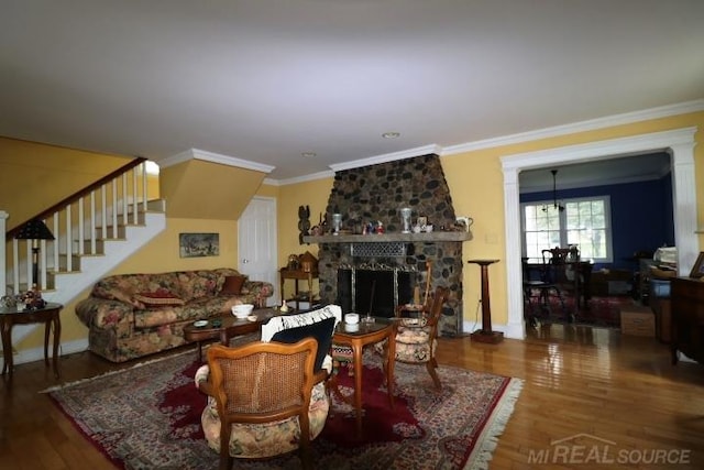 living room with wood-type flooring, a stone fireplace, and crown molding