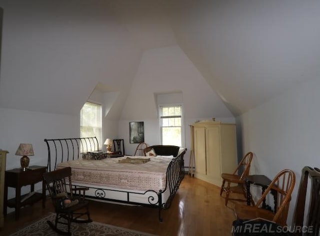 bedroom with hardwood / wood-style flooring, a baseboard radiator, and vaulted ceiling