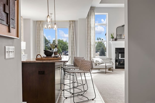 interior space featuring a healthy amount of sunlight, an inviting chandelier, a kitchen bar, and light colored carpet