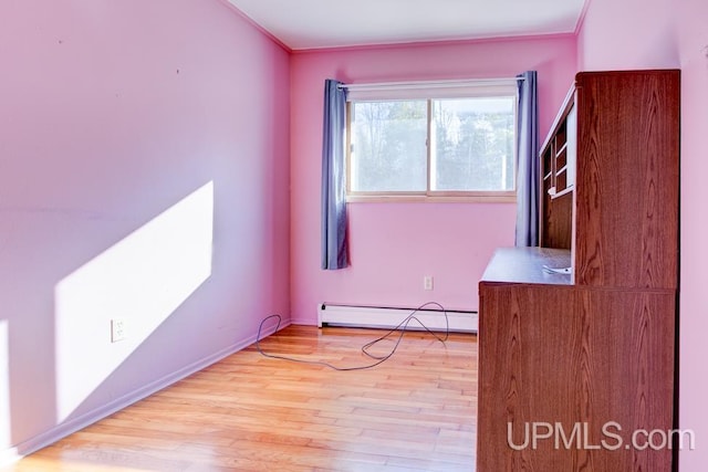 spare room featuring crown molding, a baseboard heating unit, and light hardwood / wood-style flooring