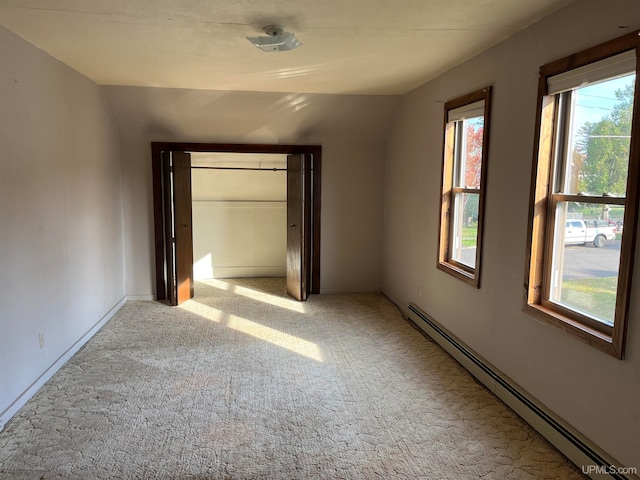 unfurnished bedroom featuring light carpet, vaulted ceiling, and baseboard heating