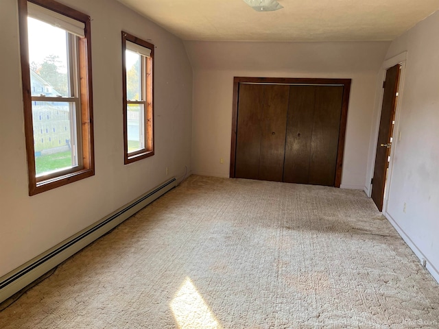 unfurnished bedroom featuring a closet, light colored carpet, lofted ceiling, and a baseboard radiator