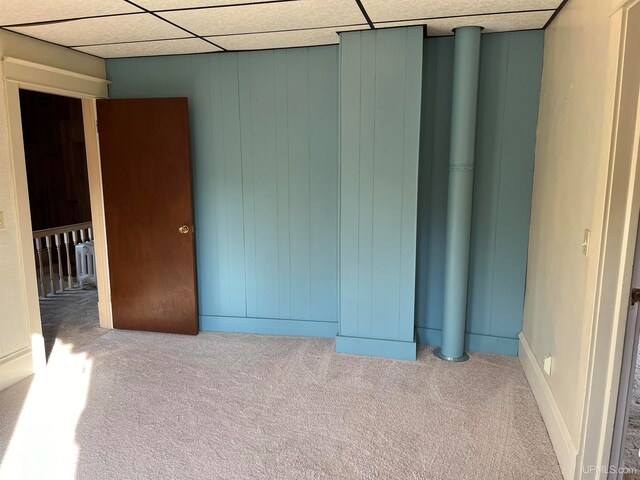 carpeted empty room with a paneled ceiling