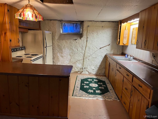 kitchen with wood walls, sink, decorative light fixtures, and white appliances