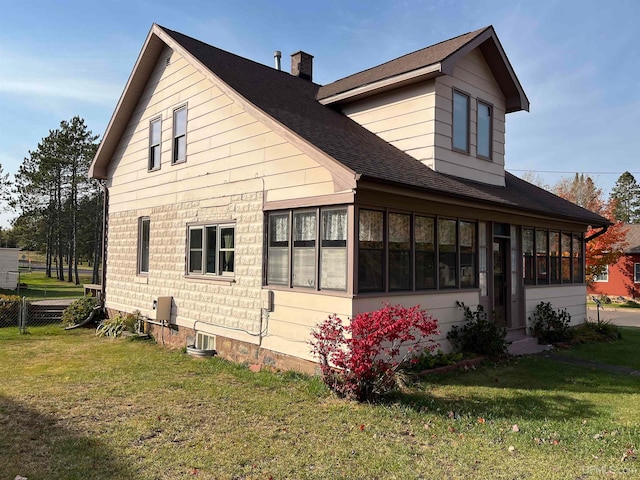 view of side of property with a lawn and a sunroom