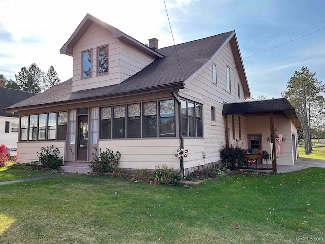 view of front of property with a front yard, a garage, and a sunroom