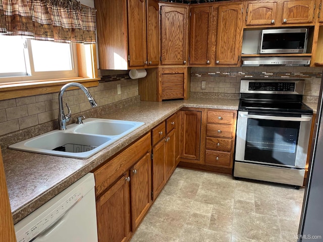 kitchen with decorative backsplash, appliances with stainless steel finishes, range hood, and sink