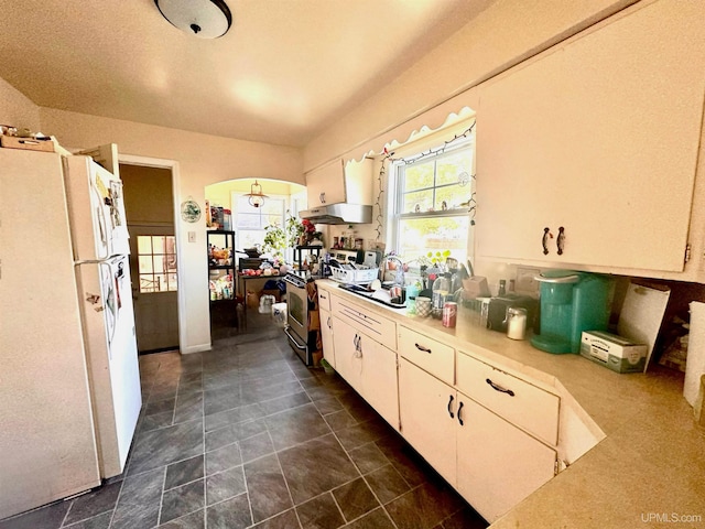 kitchen with stainless steel electric stove, sink, white fridge, and white cabinetry