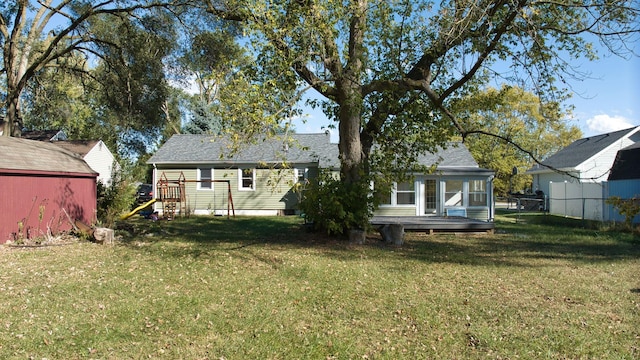 rear view of property featuring a wooden deck and a lawn