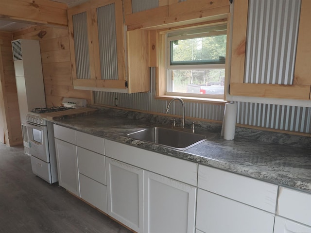 kitchen featuring sink, wooden walls, dark wood-type flooring, white cabinetry, and white range with gas cooktop