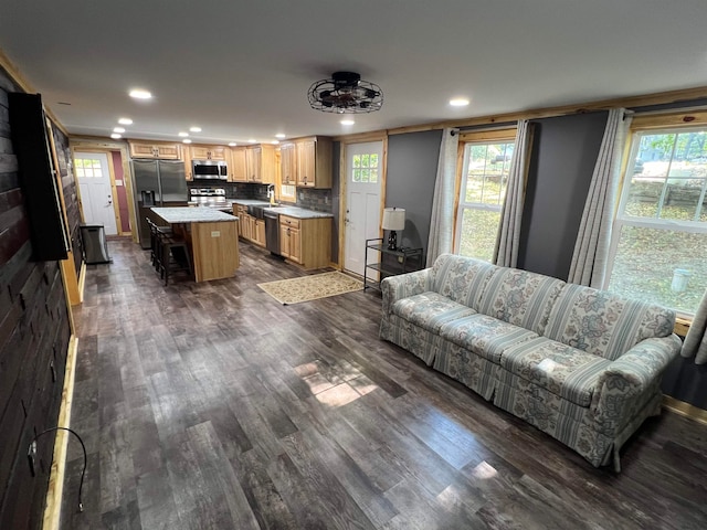 living room featuring crown molding, plenty of natural light, dark wood-type flooring, and sink