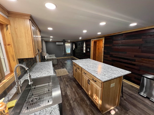 kitchen featuring wood walls, dark wood-type flooring, light stone countertops, a wall mounted AC, and a kitchen island