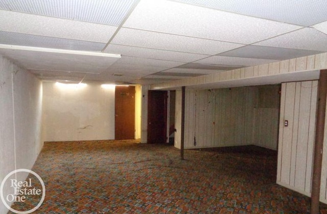 basement with wooden walls and a paneled ceiling