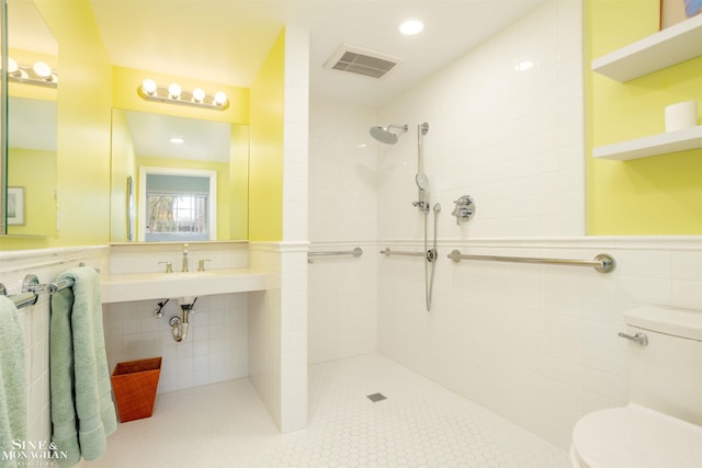 bathroom featuring a tile shower, tile walls, and toilet