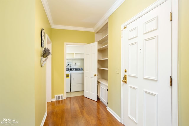 corridor with washer / clothes dryer, light hardwood / wood-style flooring, and ornamental molding