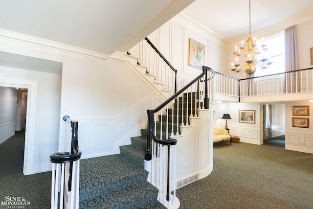 stairs featuring an inviting chandelier, ornamental molding, carpet, and a towering ceiling