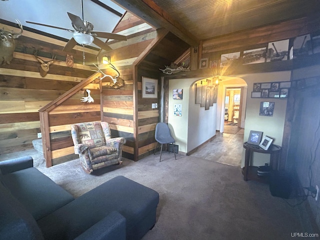 living room featuring carpet flooring, vaulted ceiling with beams, wooden walls, and ceiling fan