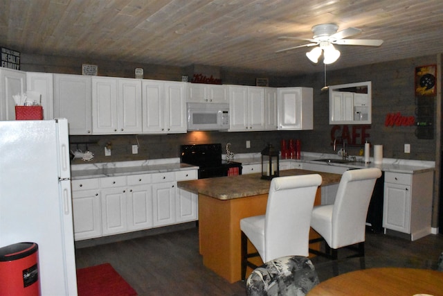 kitchen featuring ceiling fan, sink, white appliances, white cabinetry, and a center island