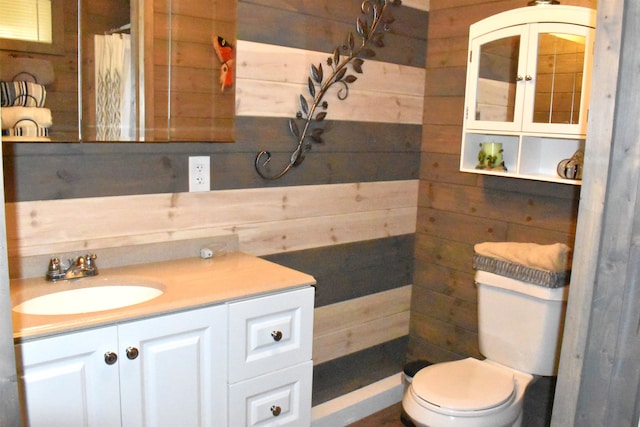 bathroom featuring walk in shower, vanity, wooden walls, and toilet