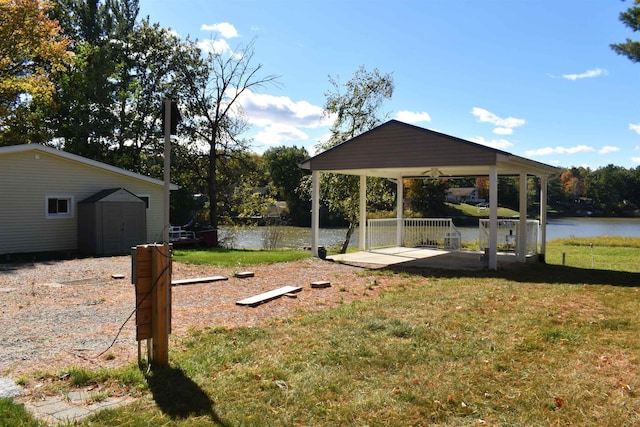 view of yard with a storage shed, a water view, and a patio area