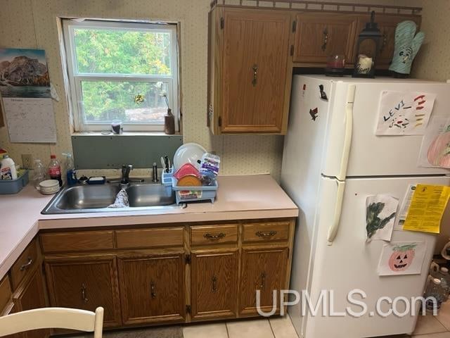 kitchen featuring white fridge, sink, and light tile patterned floors