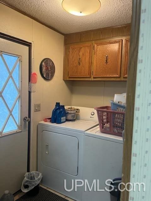 laundry room with independent washer and dryer, cabinets, and a textured ceiling