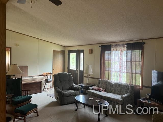 living room with ceiling fan, carpet flooring, a textured ceiling, and vaulted ceiling