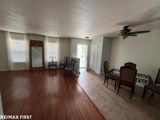 living room featuring a textured ceiling, light wood-type flooring, and ceiling fan