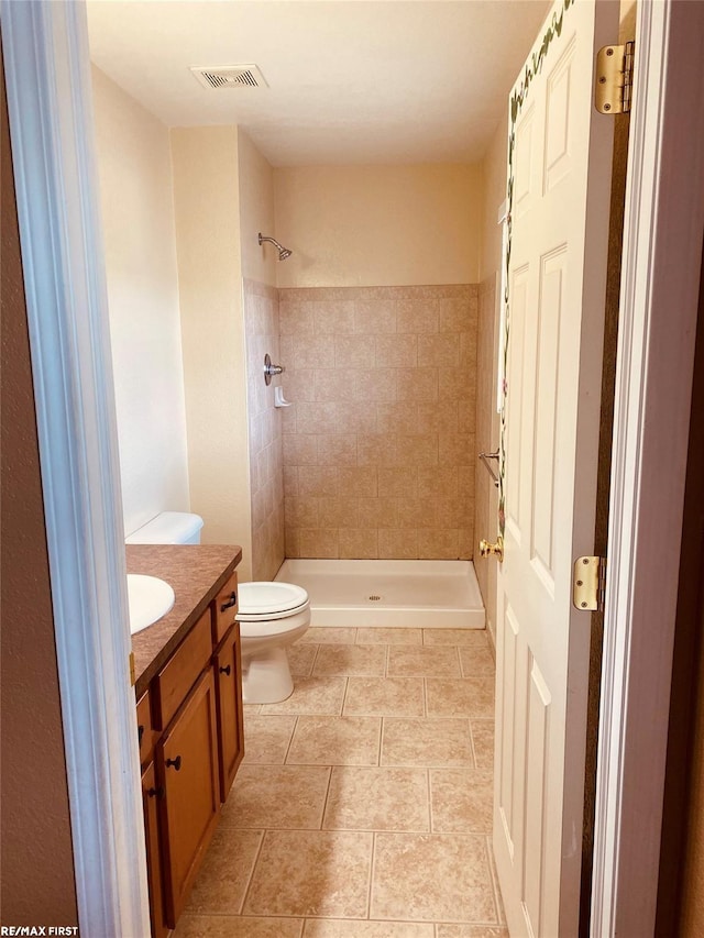 bathroom featuring toilet, vanity, and a tile shower