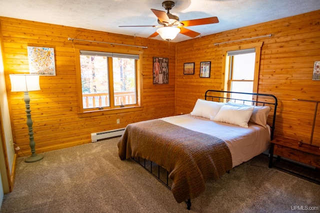 bedroom featuring carpet floors, a baseboard radiator, wood walls, and ceiling fan