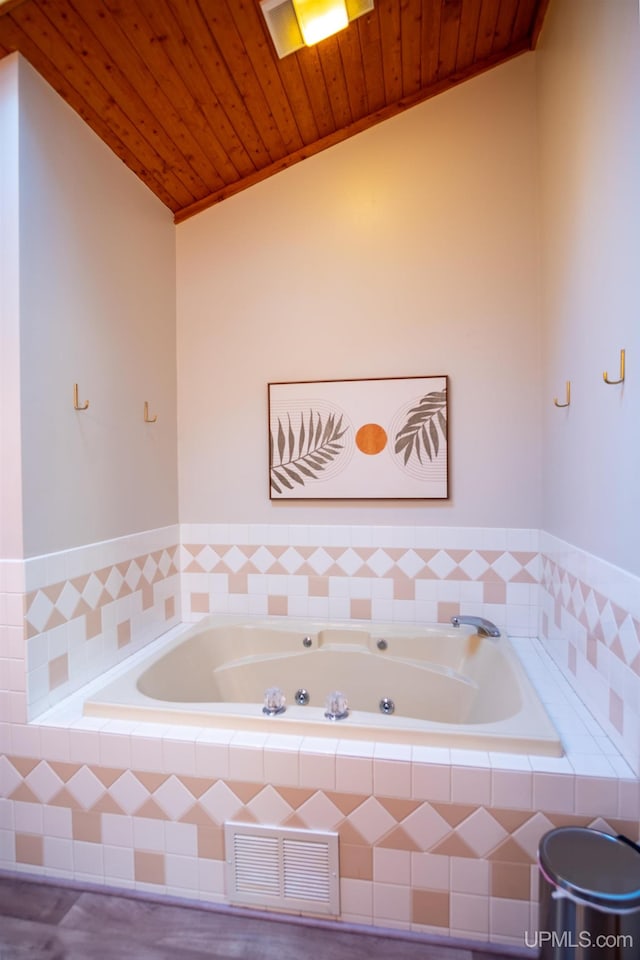 bathroom featuring tiled tub, vaulted ceiling, and wooden ceiling