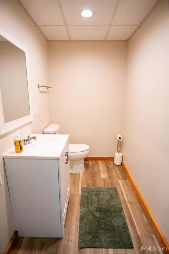 bathroom featuring a paneled ceiling, hardwood / wood-style floors, vanity, and toilet