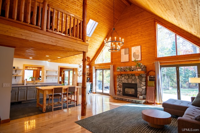 living room featuring a skylight, light wood-type flooring, high vaulted ceiling, and a healthy amount of sunlight