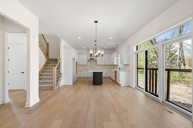 kitchen featuring hanging light fixtures, white cabinetry, a kitchen island, and a healthy amount of sunlight