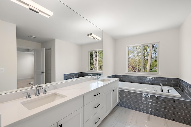 bathroom with a relaxing tiled tub and vanity