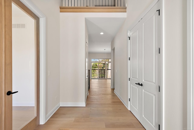 corridor featuring light wood-type flooring and a chandelier