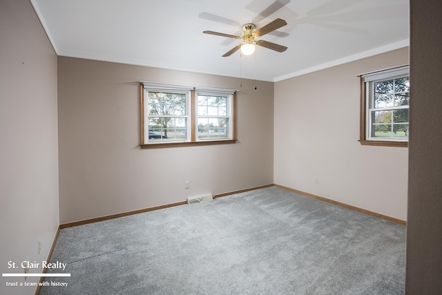 carpeted spare room with crown molding, ceiling fan, and a wealth of natural light