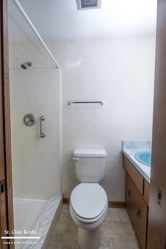 bathroom featuring toilet, vanity, tile patterned floors, and tiled shower