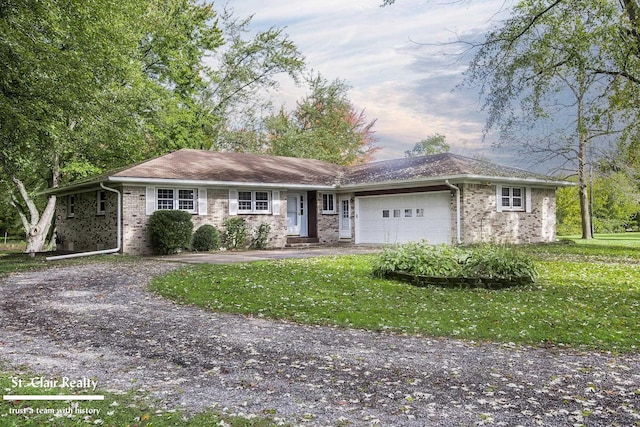 ranch-style home featuring a garage and a lawn