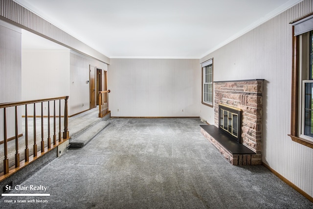 unfurnished living room with ornamental molding, a stone fireplace, and carpet floors