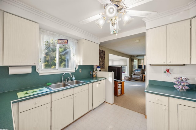 kitchen featuring sink, white dishwasher, ceiling fan, light carpet, and ornamental molding