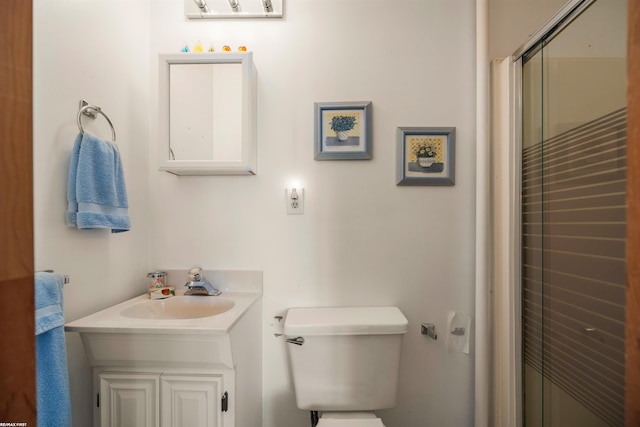 bathroom featuring vanity, a shower with shower door, and toilet